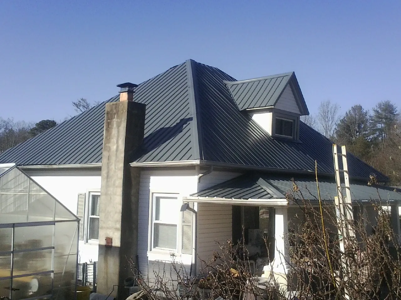 Dark blue standing seam metal roof on a white farmhouse with dormer — Slate & Tile Roof Repair by Roofing Brothers in Los Alamitos