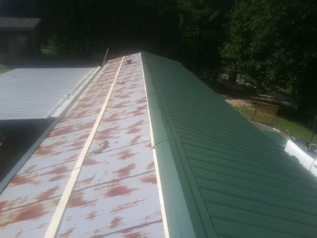 Old rusted panels beside newly installed green metal roofing — Wind Damage Roof Repair by Roofing Brothers in Los Alamitos