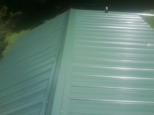 New green metal panels meeting at the ridge of a roof — Flat Roof Repair work by our crew in Los Alamitos