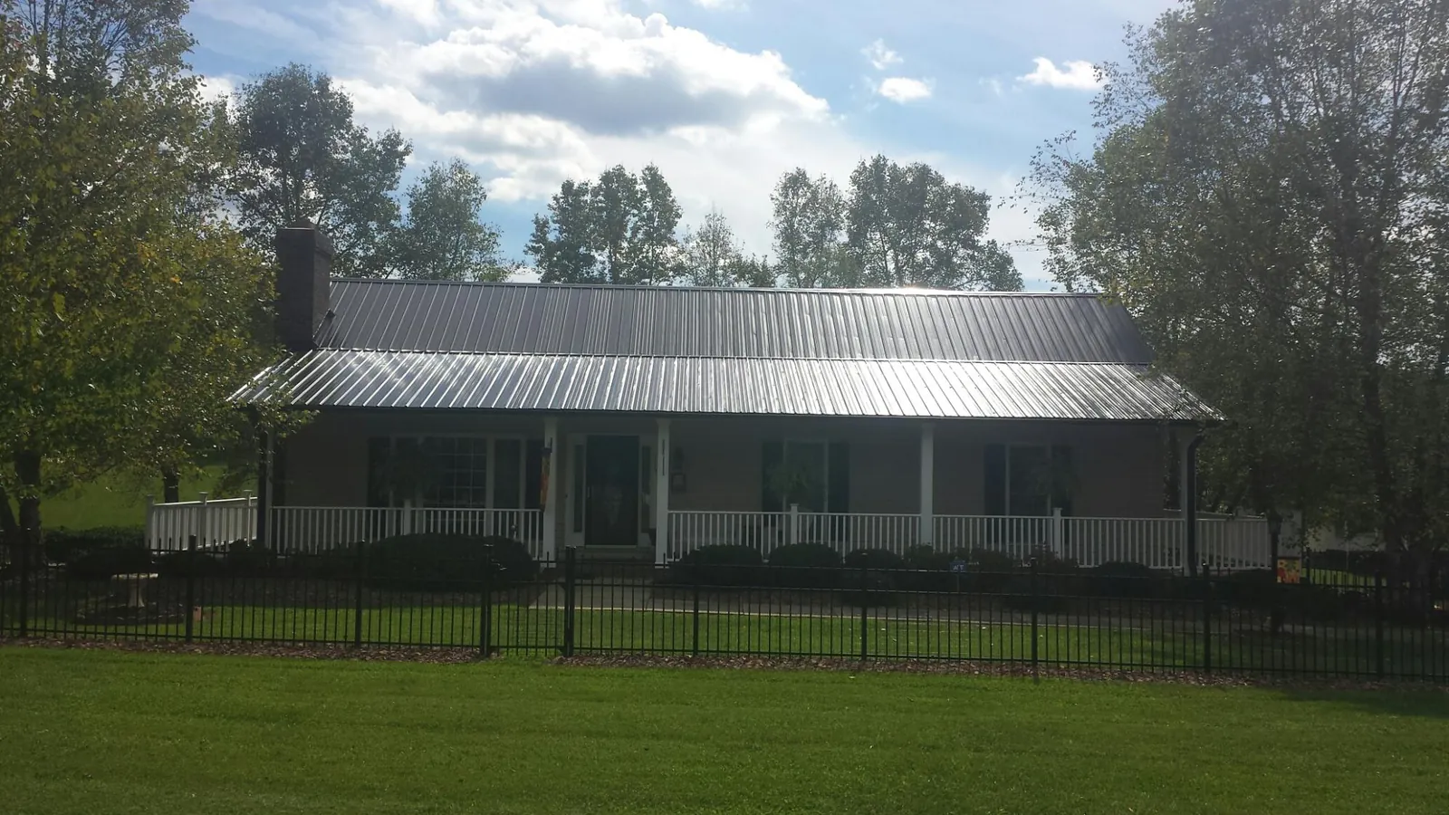 Gray metal roof on a brick ranch with a full width front porch — Gutter Guard Installation work by our crew in Los Alamitos