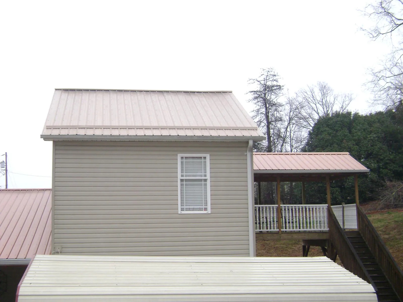 Tan metal roofs on a two story addition and attached porch, from a Roof Replacement job in Los Alamitos