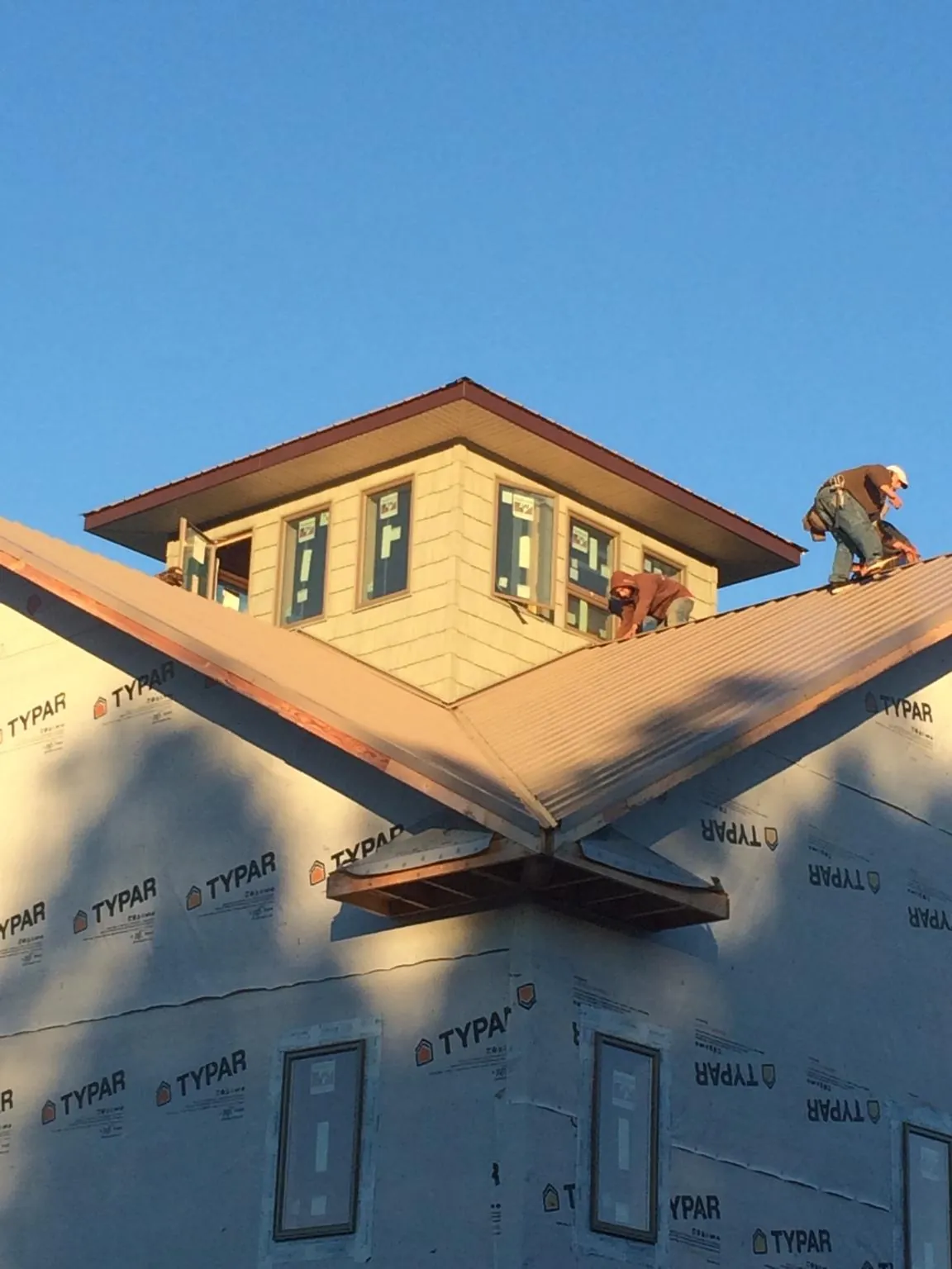 Roofers working around a rooftop cupola on a new metal roof at sunset — Roof Waterproofing in Los Alamitos by Roofing Brothers